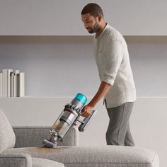 a man is using a vacuum to clean a couch with a blue and silver canister