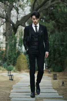 a man in a suit and tie walking down a path