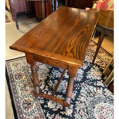 a wooden table sitting on top of a rug next to two tables with chairs in the background