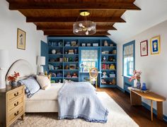 a bedroom with blue bookshelves and white bedding