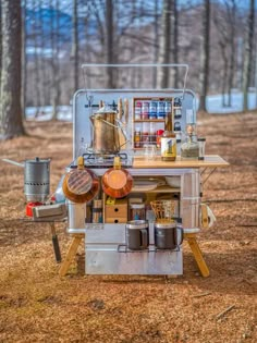 an outdoor cooking station with pots and pans on it in the middle of a wooded area