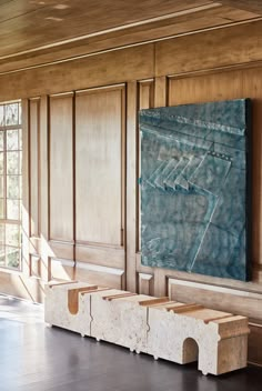 a large painting hanging on the wall in a room with wooden paneling and windows