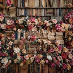 an arrangement of flowers and books are arranged on the wall in front of a bookcase