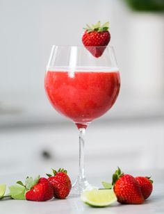 two strawberries sit on the table next to a wine glass with liquid in it