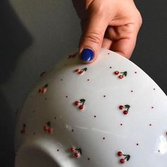 a woman's hand with blue nail polish on top of a white ceramic pig