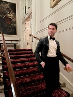 a man in a tuxedo is standing on the stairs