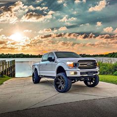 a white truck parked on top of a cement road next to a body of water