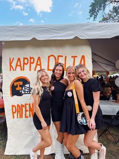 three girls are posing in front of a sign