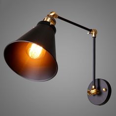 a black and gold wall light with an orange bulb hanging from it's side