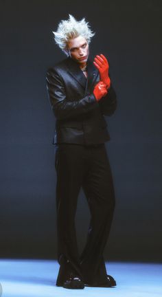 a male in a black suit and red gloves