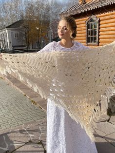 a woman is holding up a white shawl