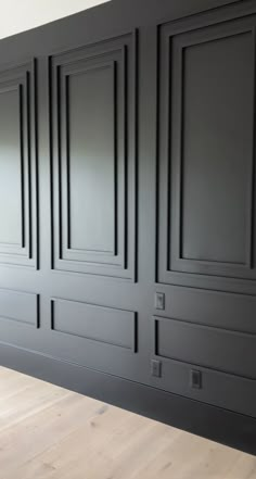 an empty kitchen with black cabinets and wood floors