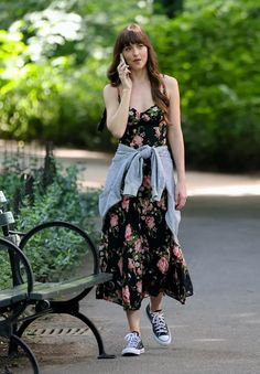 a woman walking down the street talking on her cell phone while wearing a floral dress