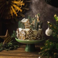 someone is sprinkling sugar on a christmas cake with gingerbread houses and trees