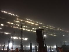 an industrial building is lit up in the fog