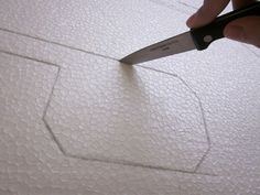 a person holding a pair of scissors cutting up some fabric on a piece of white paper