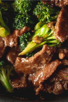 beef and broccoli with brown sauce in a black bowl on a table top