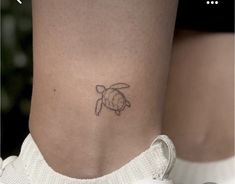 a small turtle tattoo on the side of a woman's leg, with an inscription below it