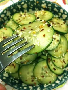 cucumber slices with sesame seeds and seasoning being held up by a fork