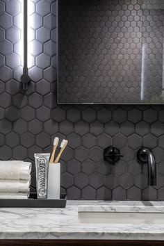 a bathroom with marble counter tops and black fixtures, along with two toothbrushes