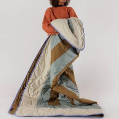 a woman is standing with her back to the camera, wrapped in an overstuffed blanket