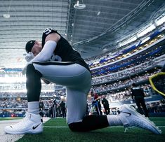 a football player kneels on the field in front of an empty stadium full of people