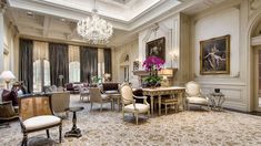 an elegant living room with chandelier and chairs