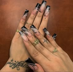 two hands with black and white nail designs on their fingers, one holding the other's hand