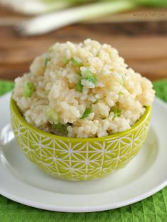 a green bowl filled with rice on top of a white plate