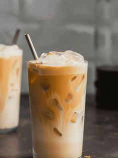 two glasses filled with iced coffee sitting on top of a table