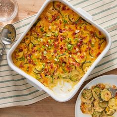 a casserole dish with zucchini and other vegetables on a striped cloth