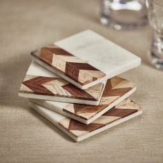 four wooden coasters sitting on top of a table next to a glass filled with water