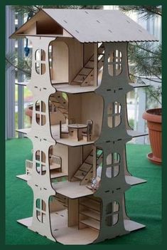 a doll house made out of cardboard on green carpeted area with potted plant