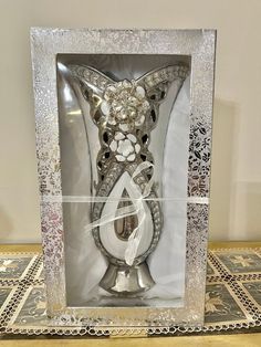 an ornate silver vase with flowers in the middle and a ribbon around it's edge