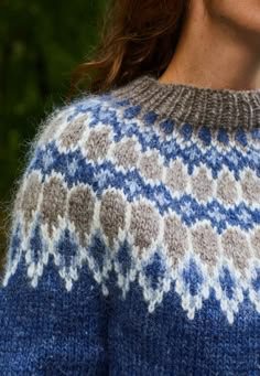 a woman wearing a blue and gray sweater