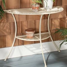 a white table with potted plants on it in front of a wood paneled wall