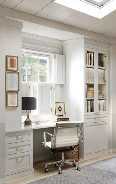 a home office with white cabinets and drawers