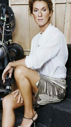 a woman sitting on top of a black bench next to a pile of film equipment