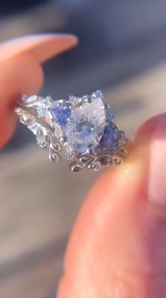 someone is holding an engagement ring with a blue and white stone in it's center