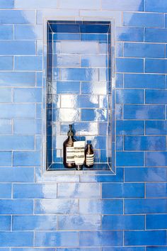 a blue tiled wall with two bottles on the window sill