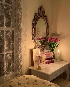 a bedroom with a bed, mirror and flowers on the table next to it is lit by two candles