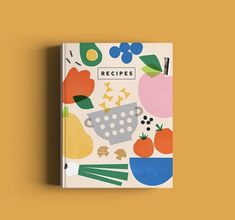 a cookbook with an illustrated image of fruits and vegetables on it, against a yellow background