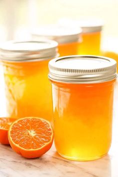 two jars filled with orange jelly sitting on top of a table