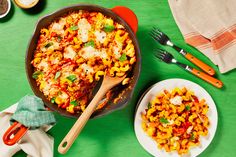 a skillet filled with macaroni and cheese on top of a green table