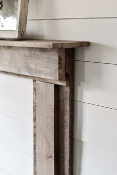 a wooden shelf with a mirror on top of it next to a white painted wall