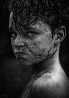 black and white photograph of a young boy with mud on his face