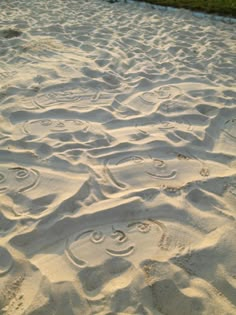 the sand has smiley faces drawn in it's white sands, and there is a grassy area to the side