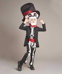 a young boy wearing a skeleton suit and top hat, holding his hands up to his face