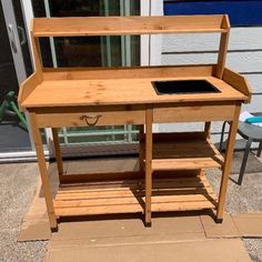 a wooden desk sitting on top of a cardboard box in front of a building with an open door