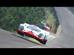 a white and red race car driving on a road next to some tall green trees